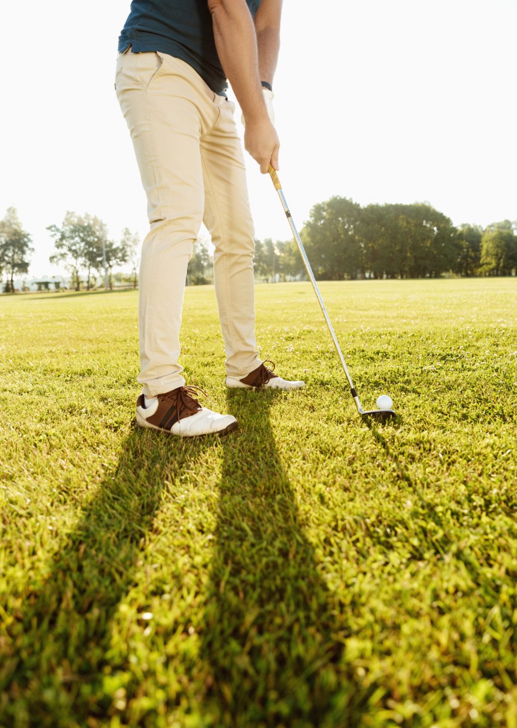 Cropped image of a golfer putting golf ball on green outdoors
